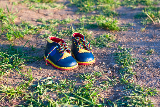 маленьке дитяче взуття на землі
 - Фото, зображення