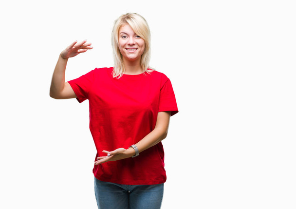 Młoda piękna kobieta blonde noszenie t-shirt czerwony na białym tle gestykulacji z rąk Wyświetlono duże i duży rozmiar znak, symbol środka. Uśmiecha się, patrząc na kamery. Koncepcji pomiaru. - Zdjęcie, obraz