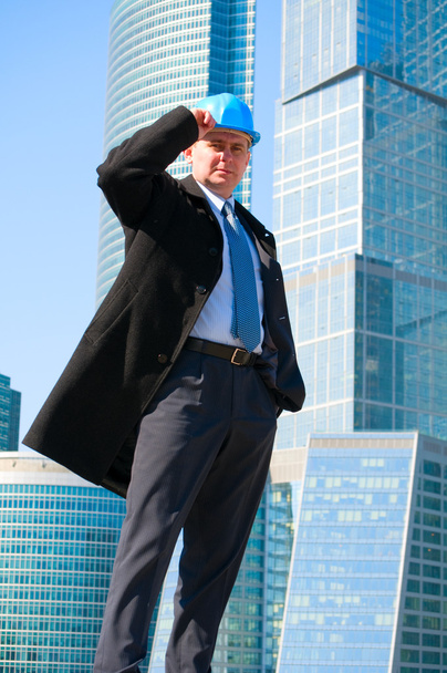 Engineer with blue hard hat near skyscrapers - Zdjęcie, obraz
