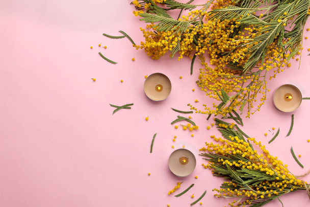 Beautiful flowers of yellow mimosa and candles on a trendy pink background. top view. free space. - Fotografie, Obrázek
