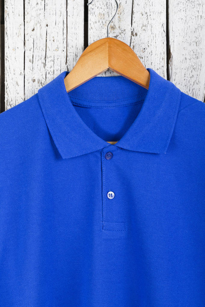 close up vista de camisa azul elegante no cabide no fundo da parede de madeira
 - Foto, Imagem