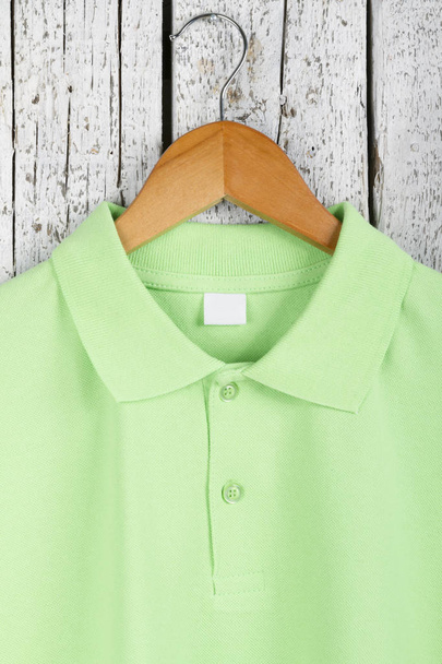Nahaufnahme von stilvollen grünen Hemd auf Kleiderbügel auf hölzernem Wandhintergrund - Foto, Bild