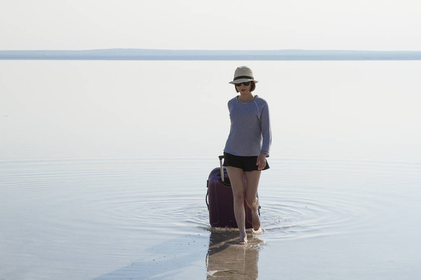 jovem mulher com bagagem andando na praia
 - Foto, Imagem