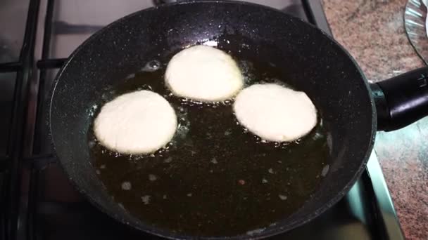 Cooking cheese pancakes in the kitchen. Cheesecakes fried in a black griddle at home. - Footage, Video