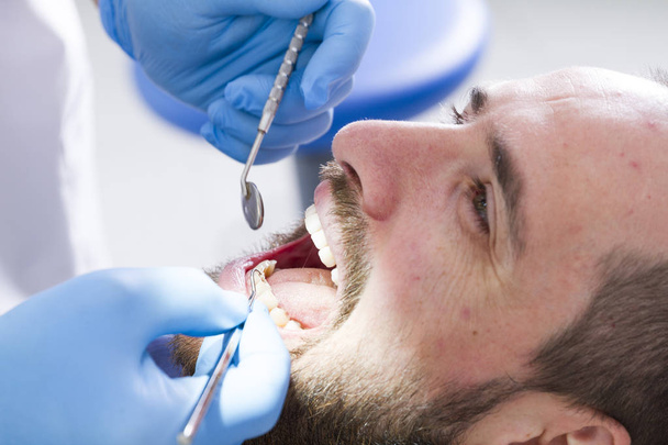 visão parcial do dentista e paciente do sexo masculino na clínica odontológica
 - Foto, Imagem