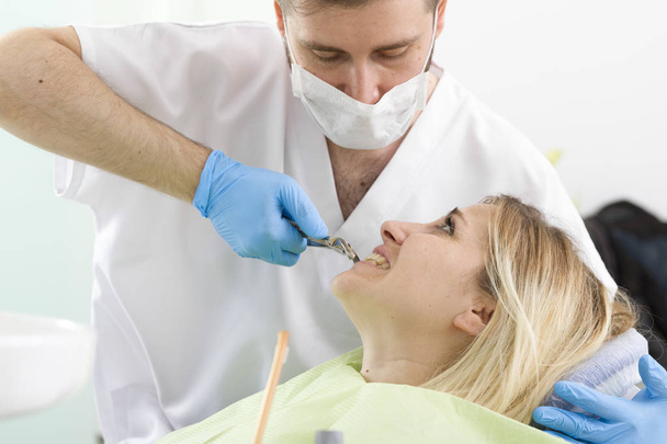 dentista do sexo masculino e jovem paciente do sexo feminino durante procedimento na clínica odontológica
 - Foto, Imagem