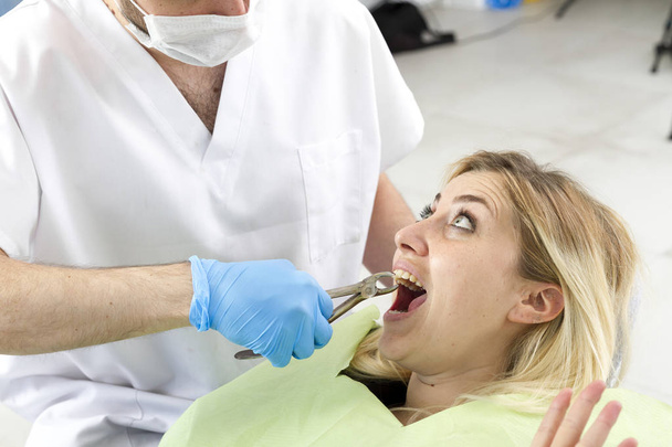 mies hammaslääkäri ja nuori naispotilas toimenpiteen aikana hammashoitolassa
 - Valokuva, kuva