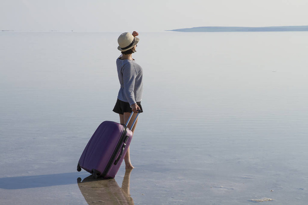 νεαρή γυναίκα με αποσκευές περπάτημα στην παραλία - Φωτογραφία, εικόνα