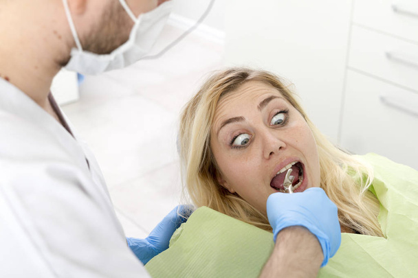 歯科医院のプロシージャの間の男性の歯科医そして若い女性の患者 - 写真・画像