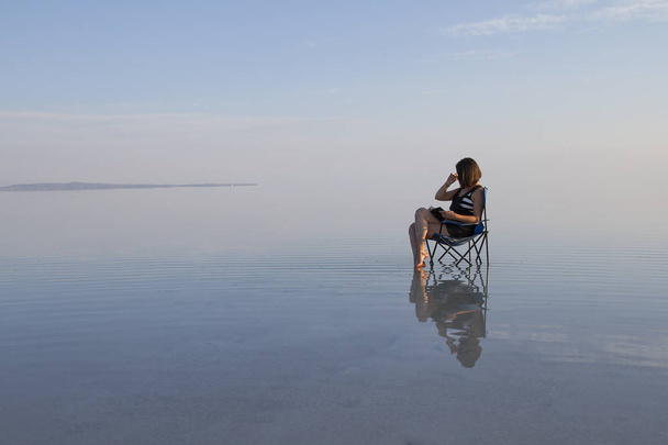 молодая женщина с книгой в кресле на берегу моря
 - Фото, изображение
