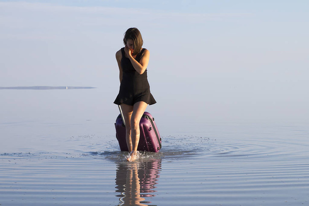 mujer joven con el equipaje caminando en la orilla del mar
 - Foto, Imagen