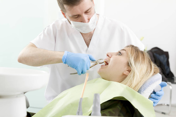 mies hammaslääkäri ja nuori naispotilas toimenpiteen aikana hammashoitolassa
 - Valokuva, kuva