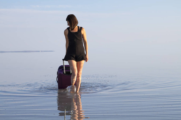 jeune femme avec bagages marchant au bord de la mer
 - Photo, image
