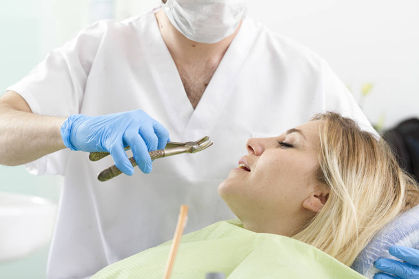 dentista do sexo masculino e jovem paciente do sexo feminino durante procedimento na clínica odontológica
 - Foto, Imagem