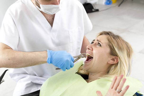 αρσενικό οδοντίατρο και νεαρή γυναίκα ασθενής κατά τη διάρκεια της διαδικασίας στην οδοντιατρική κλινική - Φωτογραφία, εικόνα