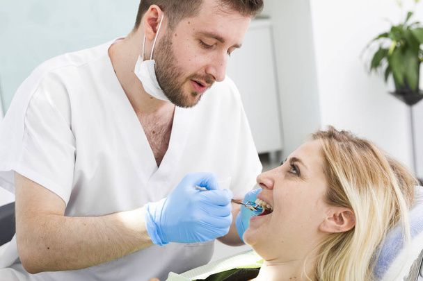 dentista masculino y paciente joven durante el procedimiento en la clínica dental
 - Foto, Imagen