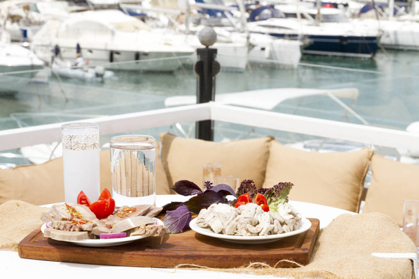 vista de cerca de la mesa servida con diferentes platos con barcos en el telón de fondo
 - Foto, Imagen