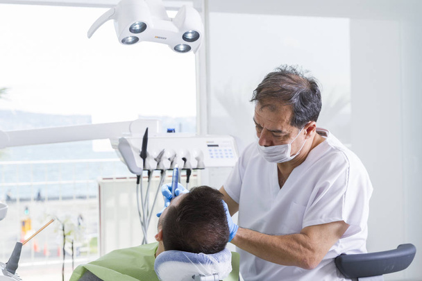 dentista e paciente do sexo masculino durante o procedimento na clínica odontológica
 - Foto, Imagem
