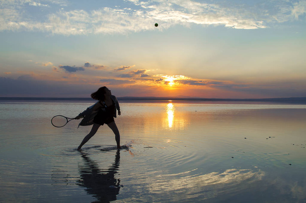 femme jouant au tennis au bord de la mer pendant le coucher du soleil
 - Photo, image