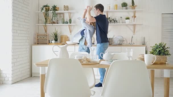 šťastná žena tančí na servírované stolce v moderní kuchyni - Záběry, video