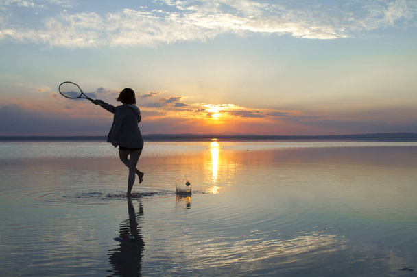 mujer jugando tenis en la orilla del mar durante el atardecer
 - Foto, Imagen