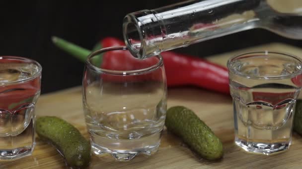 Giet wodka in shot glazen, geplaatst op een houten bord - Video