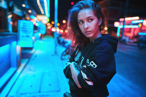 Neon close up portrait of young woman wear hoodie. night city street shot - Foto, Imagem