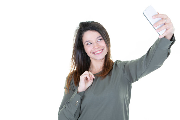 Портрет молодой привлекательной женщины, делающей селфи фото со смартфоном на белом фоне
 - Фото, изображение