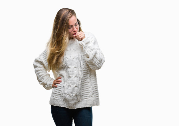 若い美しい金髪女性は体調不良や風邪や気管支炎の症状として咳を感じて孤立の背景に冬のセーターとサングラスを着用します。ヘルスケアの概念. - 写真・画像