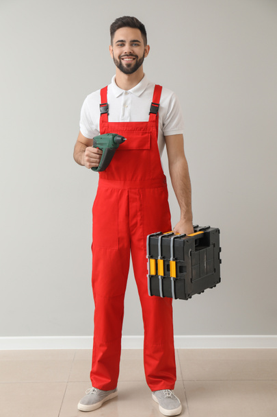Male worker with drill and tools kit near light wall - Zdjęcie, obraz