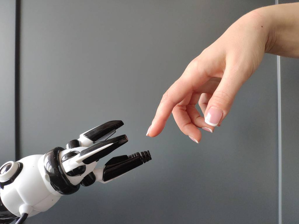 A mão de uma mulher estende-se à mão de um robô, parece o afresco de Michelangelo.
. - Foto, Imagem