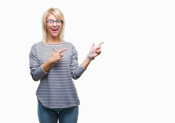 Young beautiful blonde woman wearing glasses over isolated background smiling and looking at the camera pointing with two hands and fingers to the side. - Foto, Imagem