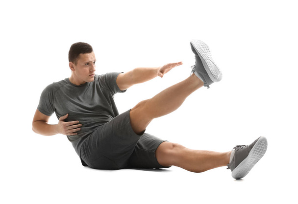 Sporty young man training against white background - Foto, afbeelding