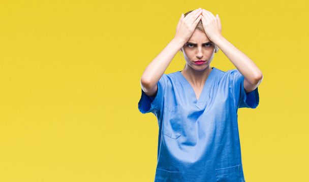 Young beautiful blonde doctor surgeon nurse woman over isolated background suffering from headache desperate and stressed because pain and migraine. Hands on head. - Photo, Image