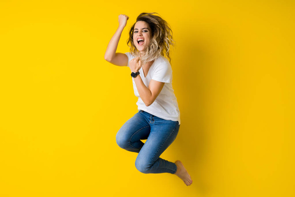 Mooie jonge blonde vrouw gelukkig en vieren met springen  - Foto, afbeelding