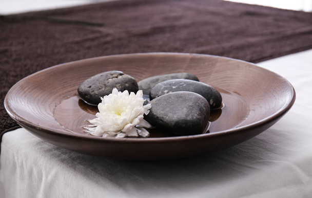 Assiette avec pierres de massage et fleur sur la table dans le salon de spa
 - Photo, image