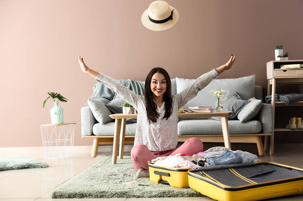 Young woman having fun while packing suitcase at home. Travel concept - Φωτογραφία, εικόνα