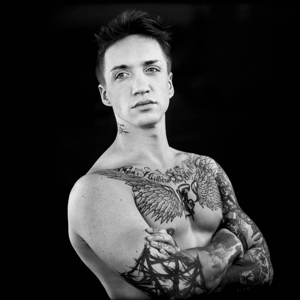 Hombre tatuado posando con los brazos cruzados
. - Foto, imagen