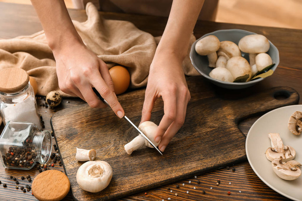 Женщина режет сырые грибы за столом на кухне
 - Фото, изображение