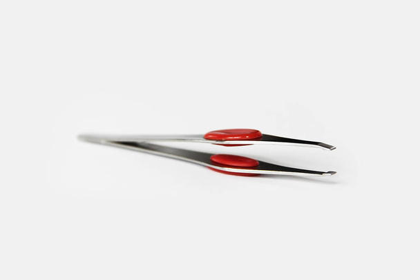 pinzas de metal de diseño con inserto de plástico rojo sobre un fondo blanco
 - Foto, Imagen