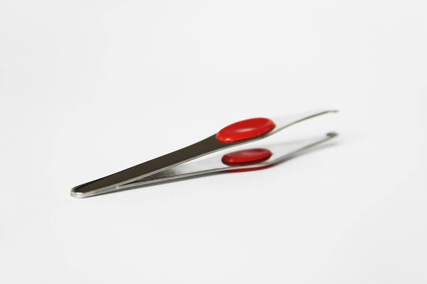 pinças de metal designer com inserção de plástico vermelho em um fundo branco
 - Foto, Imagem