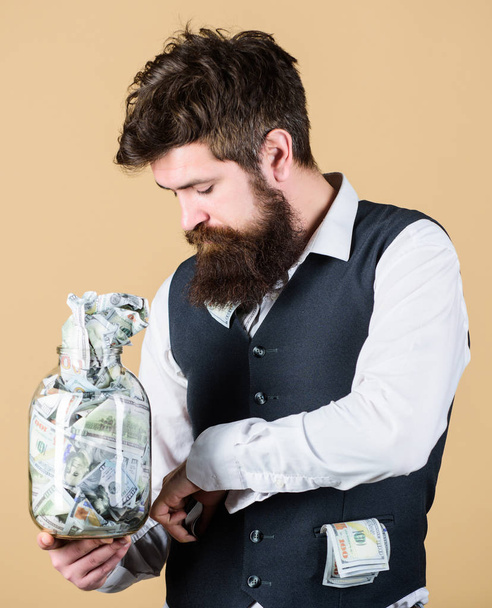 Start saving for your retirement as early as possible. Establish your budget. Businessman with his dollar savings. Security and cash money savings. Man bearded guy hold jar full of cash savings - Valokuva, kuva