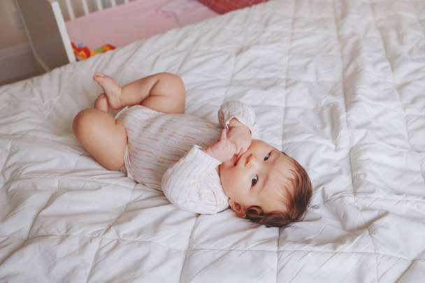 Retrato de linda adorable niña asiática de raza mixta de cuatro meses acostada en la cama en el dormitorio. Emoción natural cara expresión. Diversidad infantil estilo de vida. Vista desde arriba
. - Foto, imagen