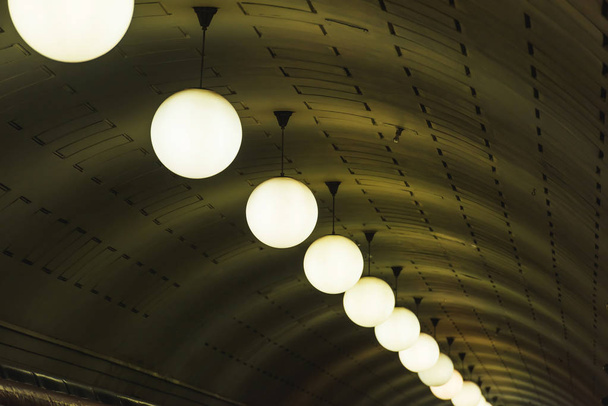 Oświetlenie w stacji metra. Lampy żarowe zawarte. Uwypuklenie sufit. Żyrandole szklane okrągłe. - Zdjęcie, obraz