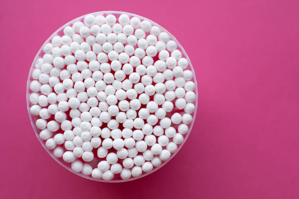 Closeup view from above on round pack of cotton buds on pink background - Fotó, kép
