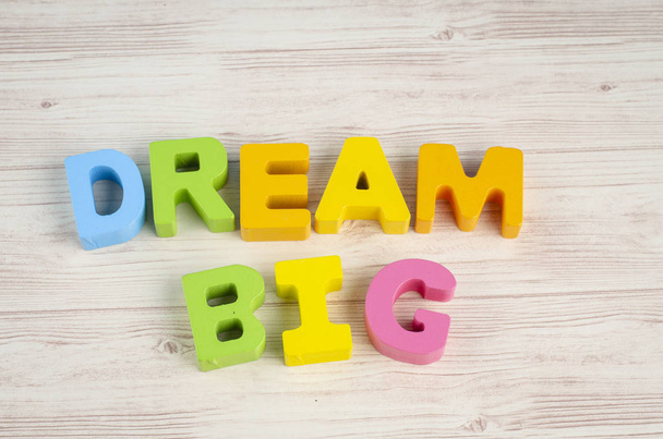 DREAM BIG  word on wooden desk over blue background - Photo, Image