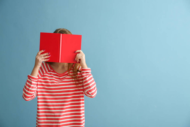 Schoolgirl with book on color background - Foto, imagen
