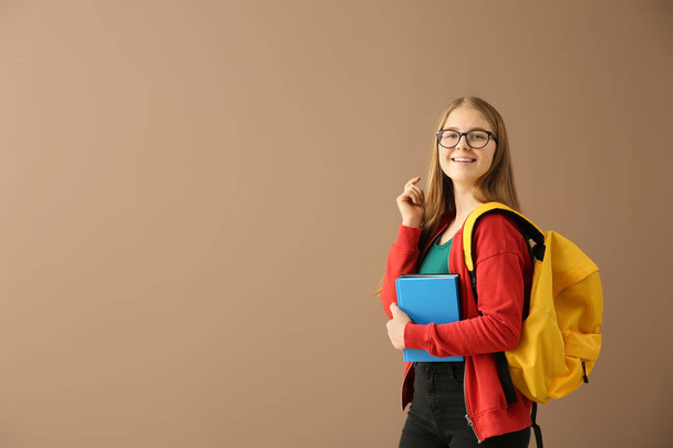 Schoolmeisje met boeken over kleur achtergrond - Foto, afbeelding