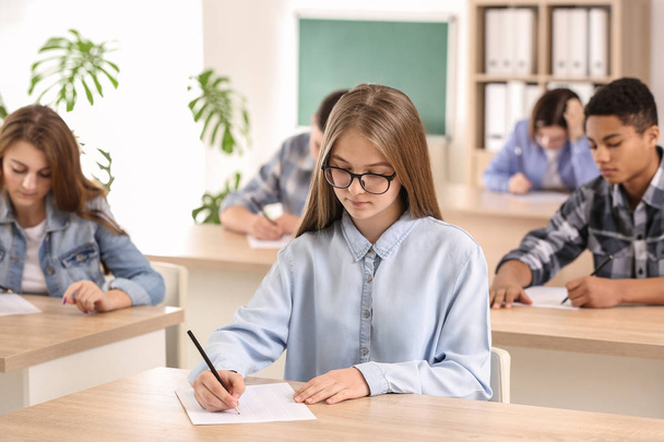 Pupils passing school test in classroom - 写真・画像