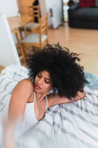 Giovane donna nera in lingerie sdraiata sul letto in camera
 - Foto, immagini